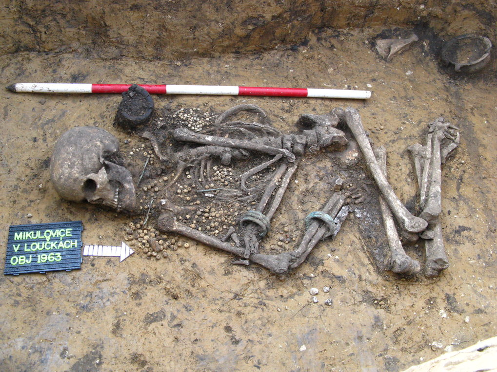 Das Bild des Skelettes im Grab aus der frühen Bronzezeit. Am Körper des Verstorbenen ist Schmuck als Grabbeigabe zu sehen.