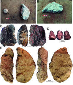 Ochre pieces and stone processing equipment layingon a red-stained pigment patch.